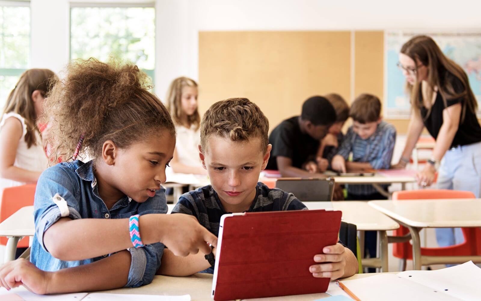 Two elementary aged students using an iPad in a classroom